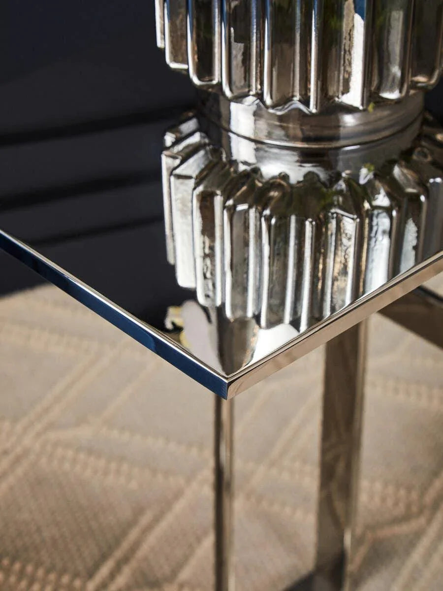 Modern glass top side table with chrome legs and textured metallic base detail