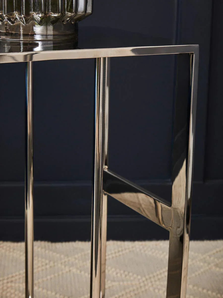 chrome side table with glass vase, close-up of metal legs on textured rug