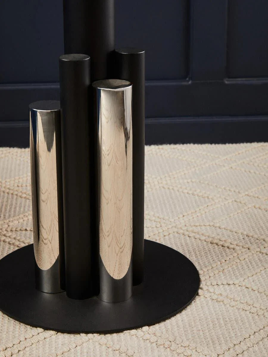Black and chrome metal dining table base on textured cream rug