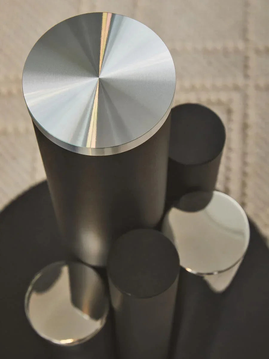 Brushed metal coffee table detail with cylindrical metal accents and matte black finish