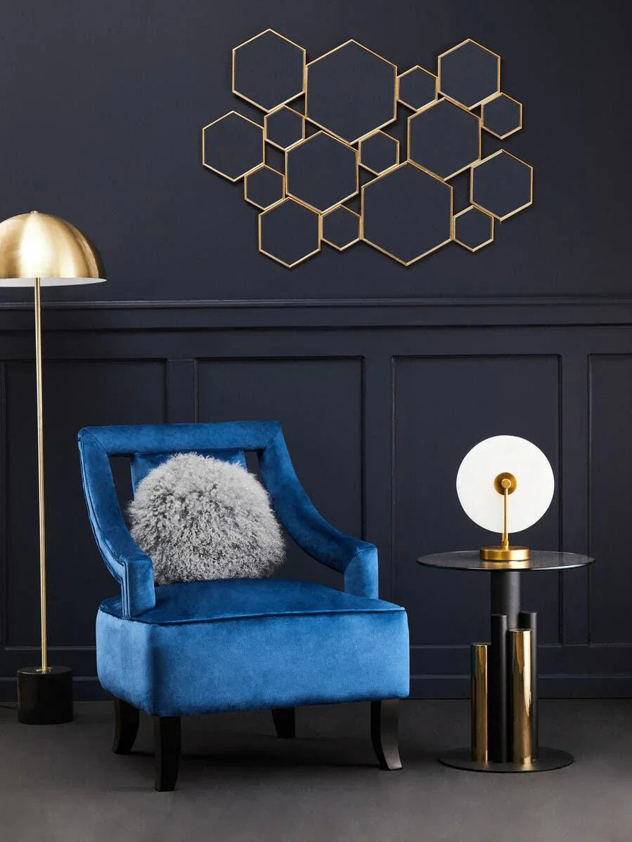 Blue velvet accent chair with grey faux fur cushion, gold floor lamp, and geometric wall art
