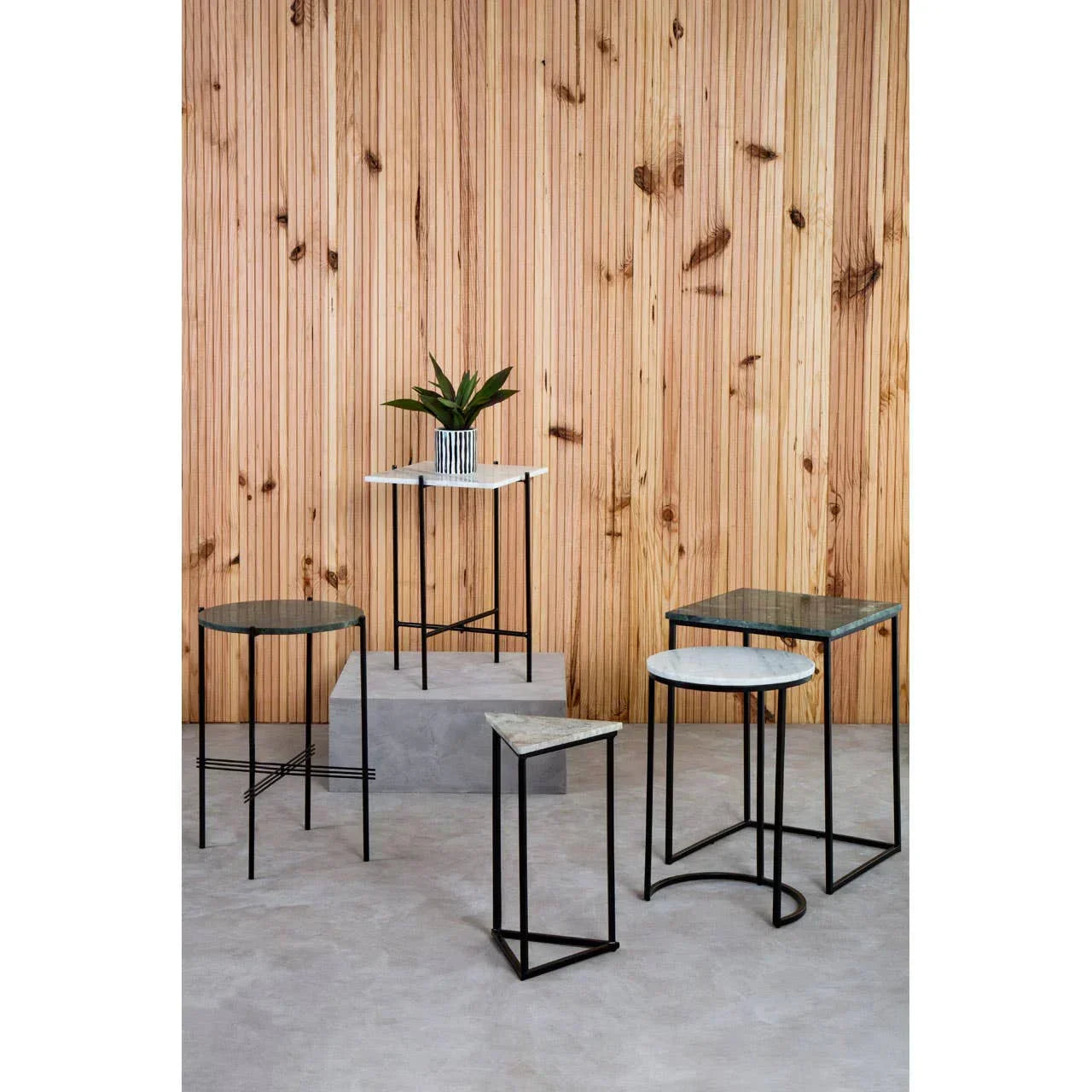Set of marble top side tables with black metal frames against wooden panel wall