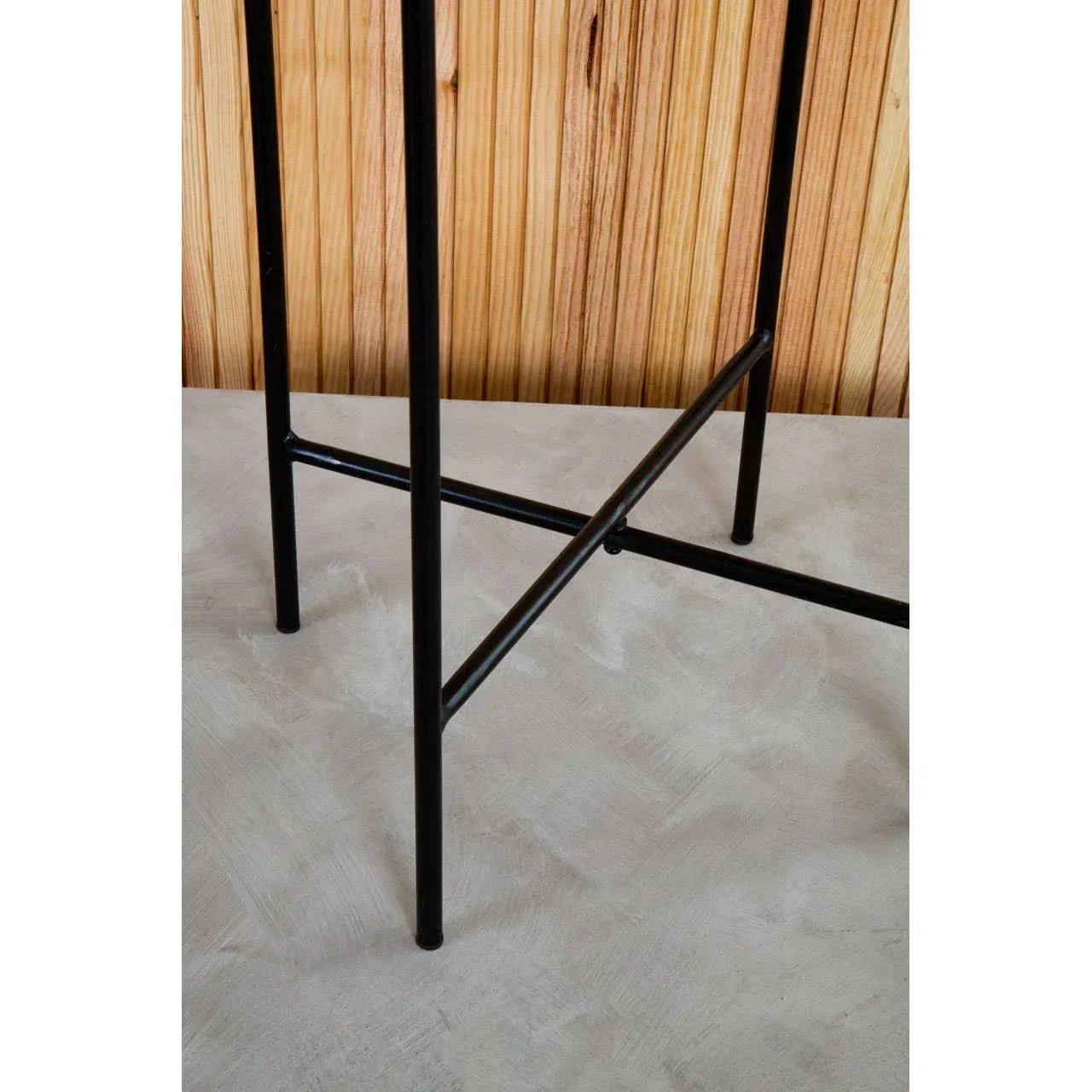 Black metal bar stool legs with cross support on grey floor and wood panel background