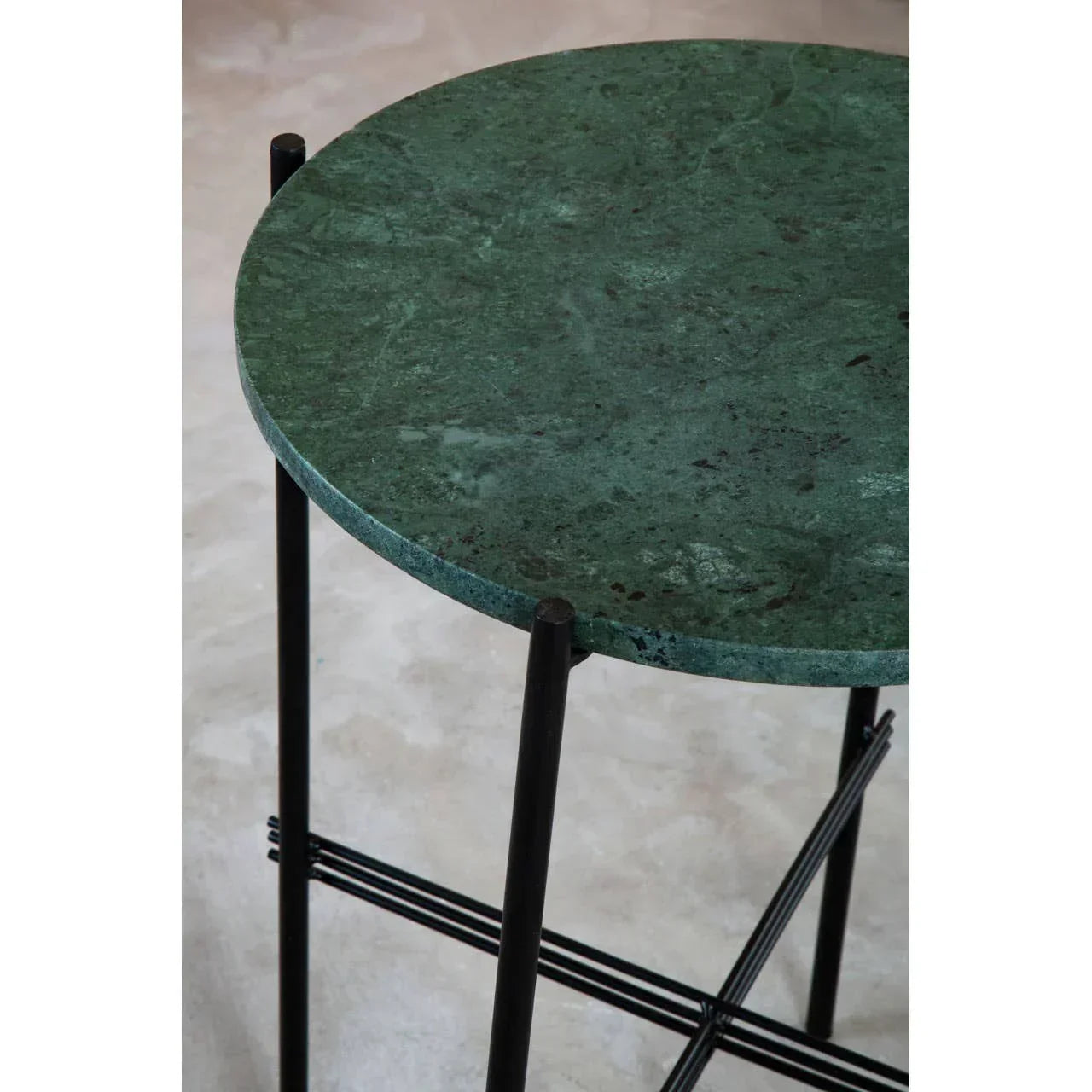 Green marble side table with round top and black metal frame on light floor