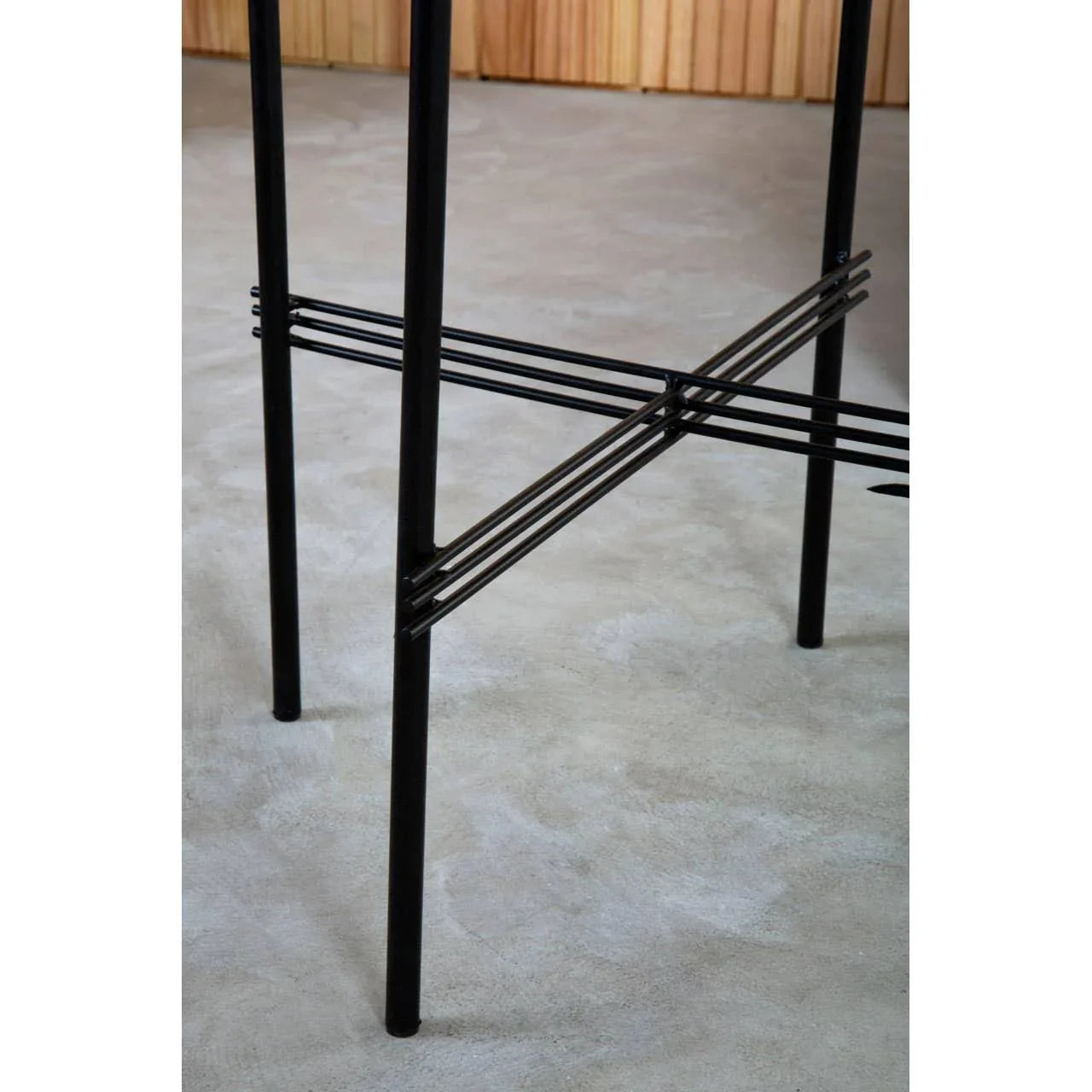 Black metal bar stool legs with crossbar support on concrete floor