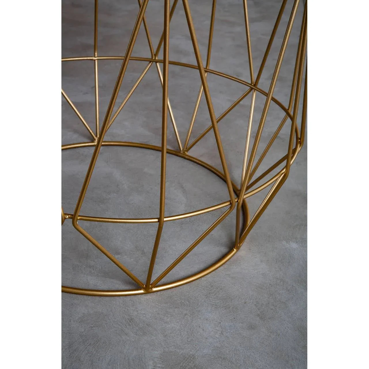 Gold metal table base with geometric frame on concrete floor
