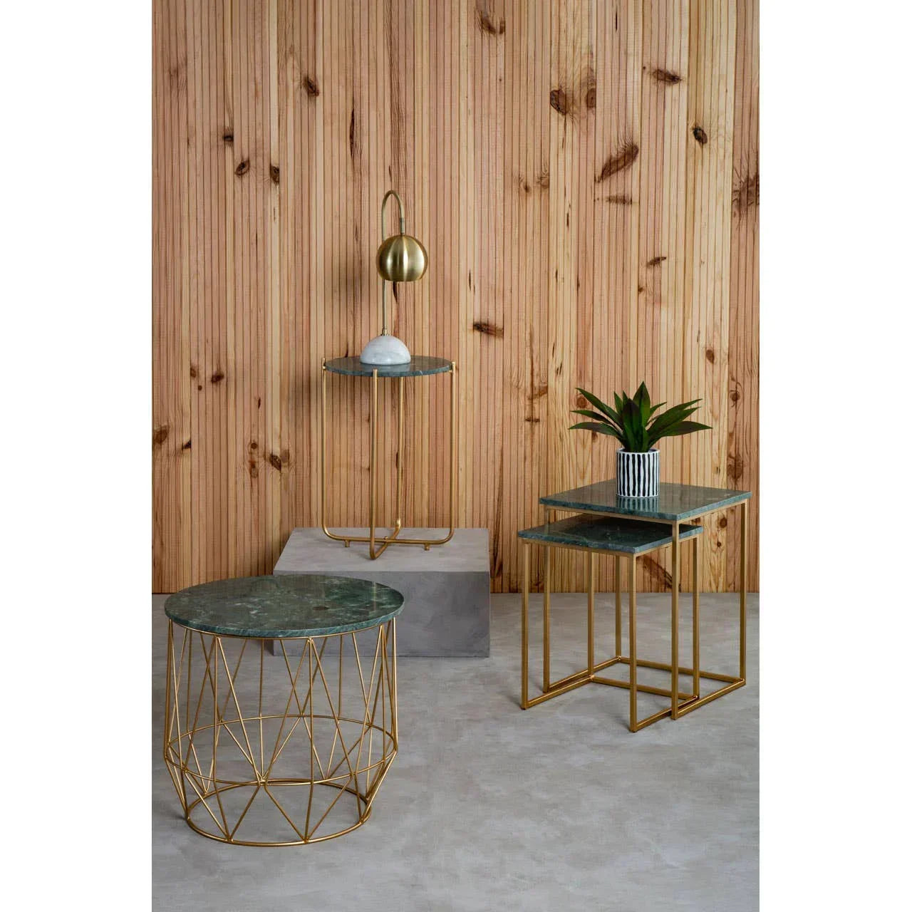 Set of marble top side tables with gold metal frames and plant decor against wooden wall