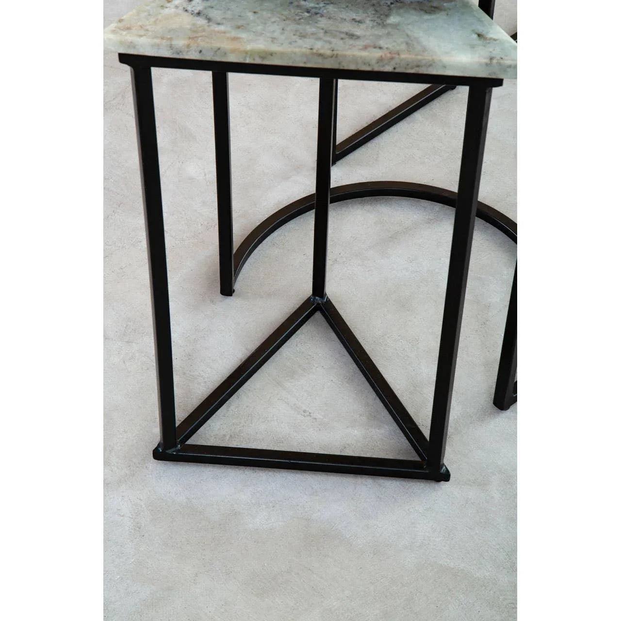 Metal side table with black geometric frame and marble effect top on light floor
