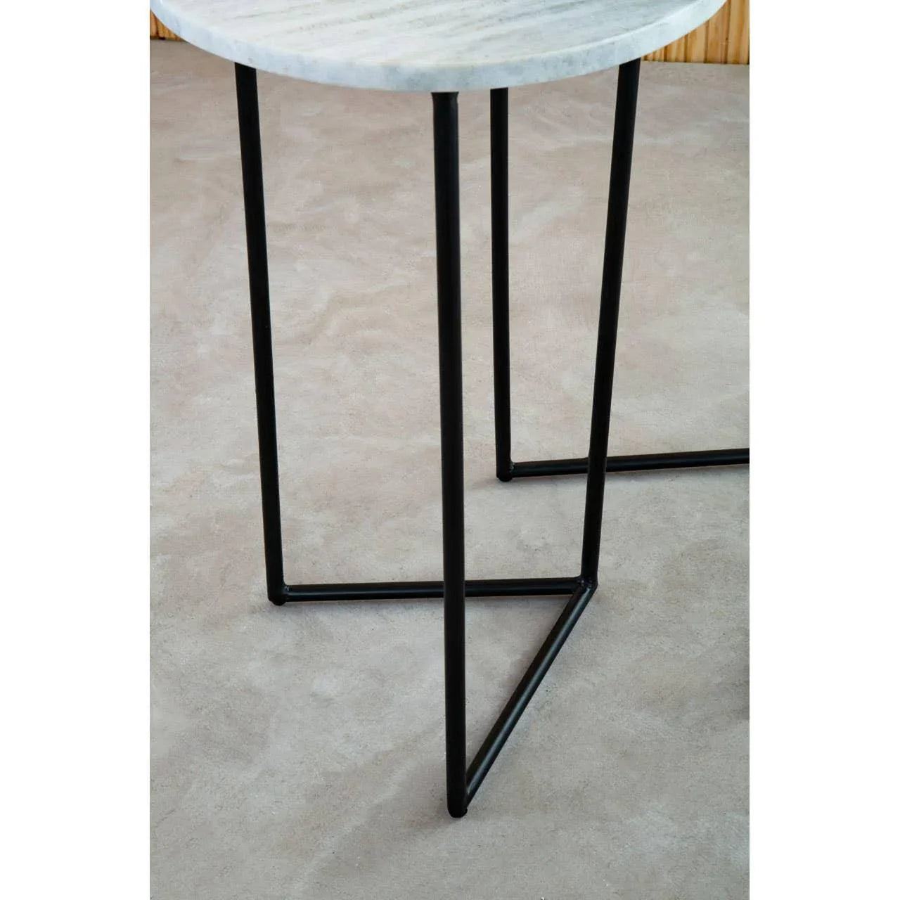 Round side table with white marble top and black metal legs on light floor
