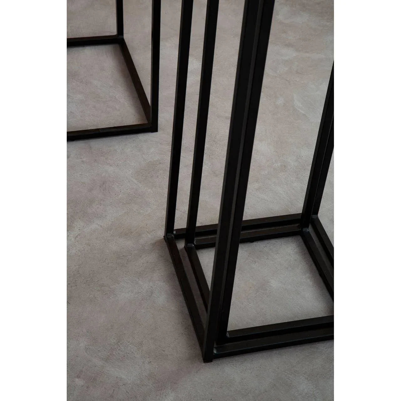 Black metal table frames with square bases on a light grey floor