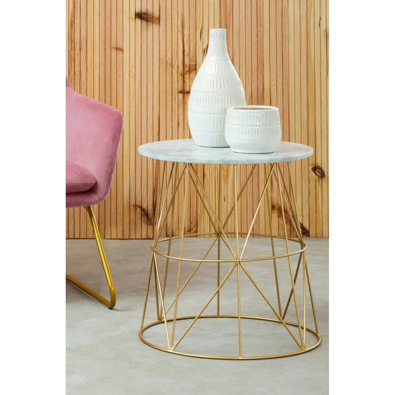 marble top side table with gold metal base and white vases beside pink velvet chair