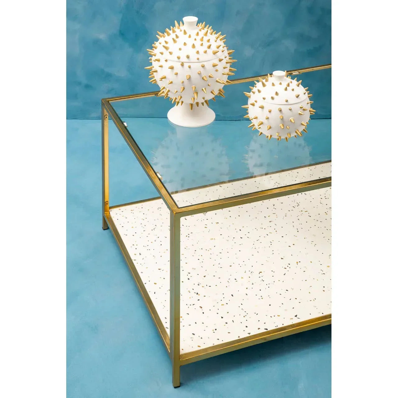 Glass coffee table with gold frame and terrazzo shelf, decorative white and gold vases on top