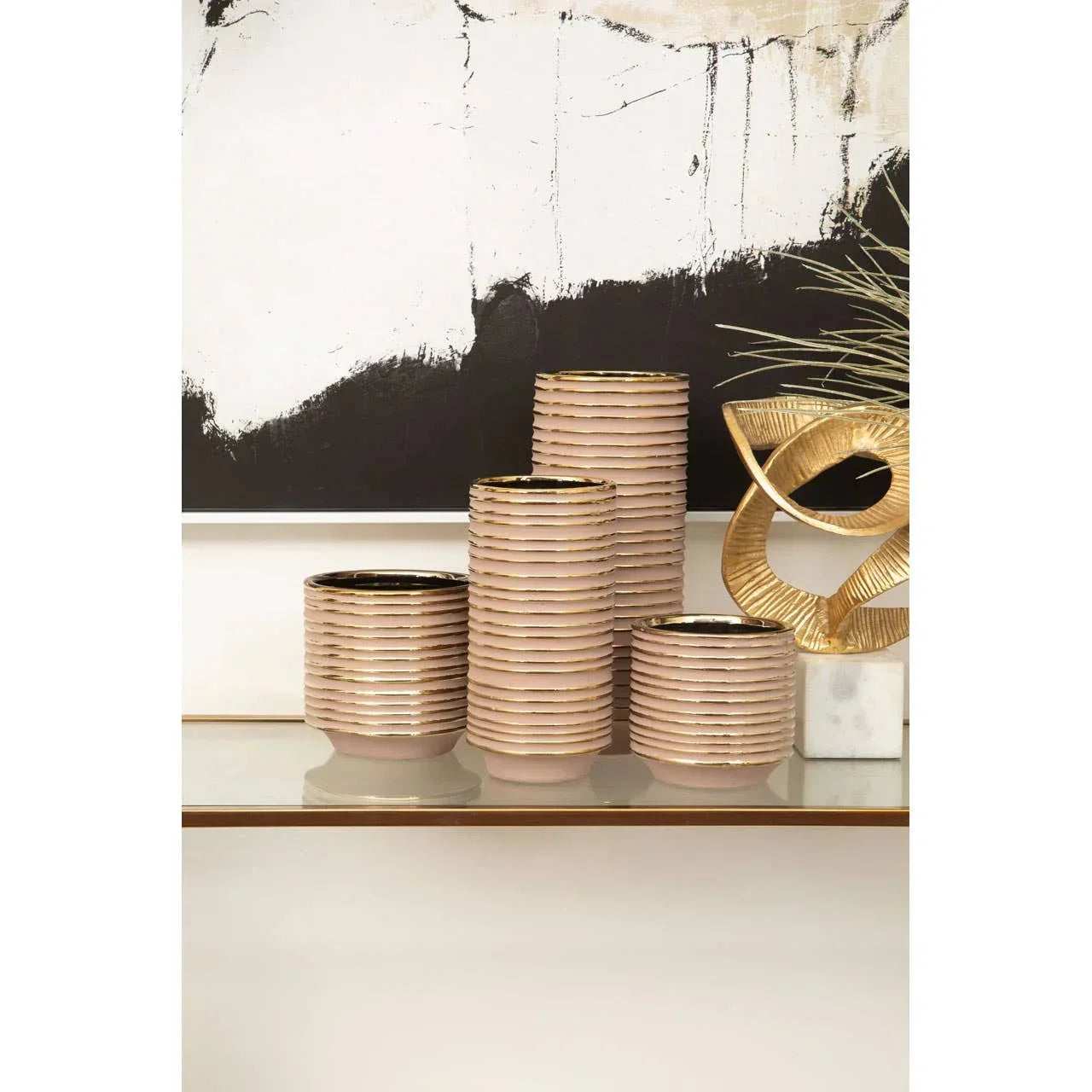 Set of ribbed ceramic planters with gold rims on a glass console table