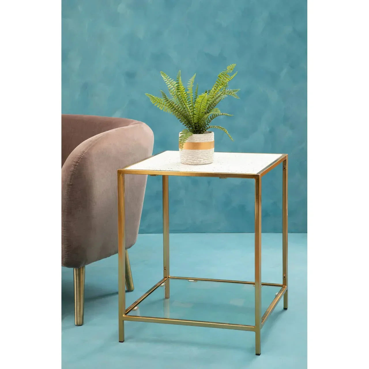 Gold frame side table with white top and potted plant beside beige armchair