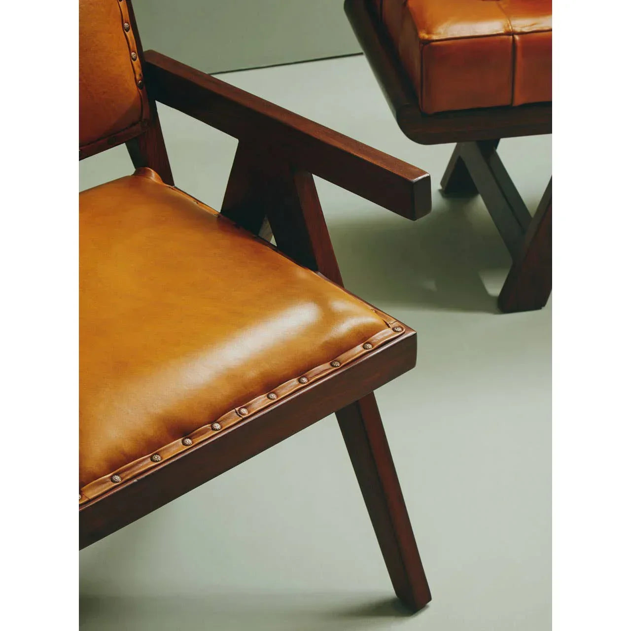Close-up brown leather armchair with studded trim and dark wood frame