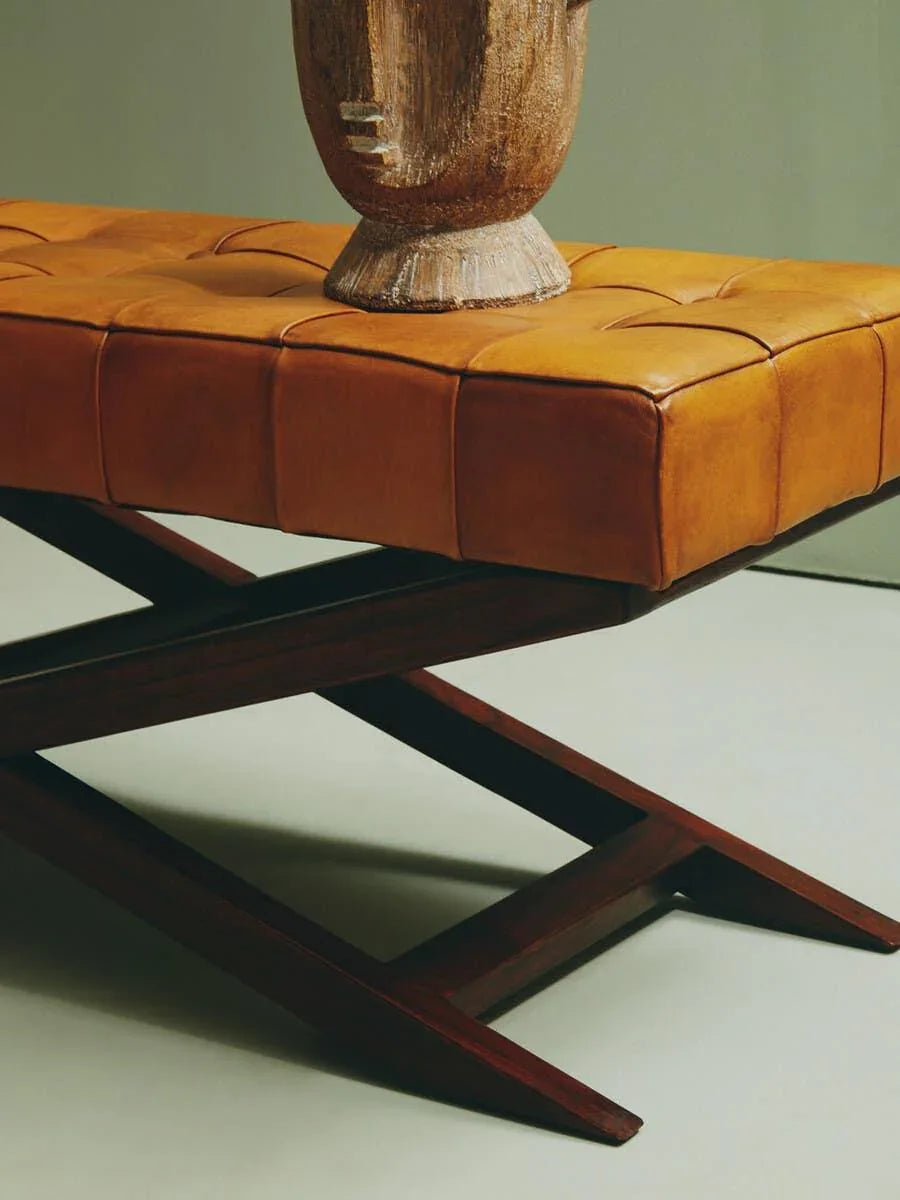 Tan leather bench with tufted cushion and dark wooden X-frame legs