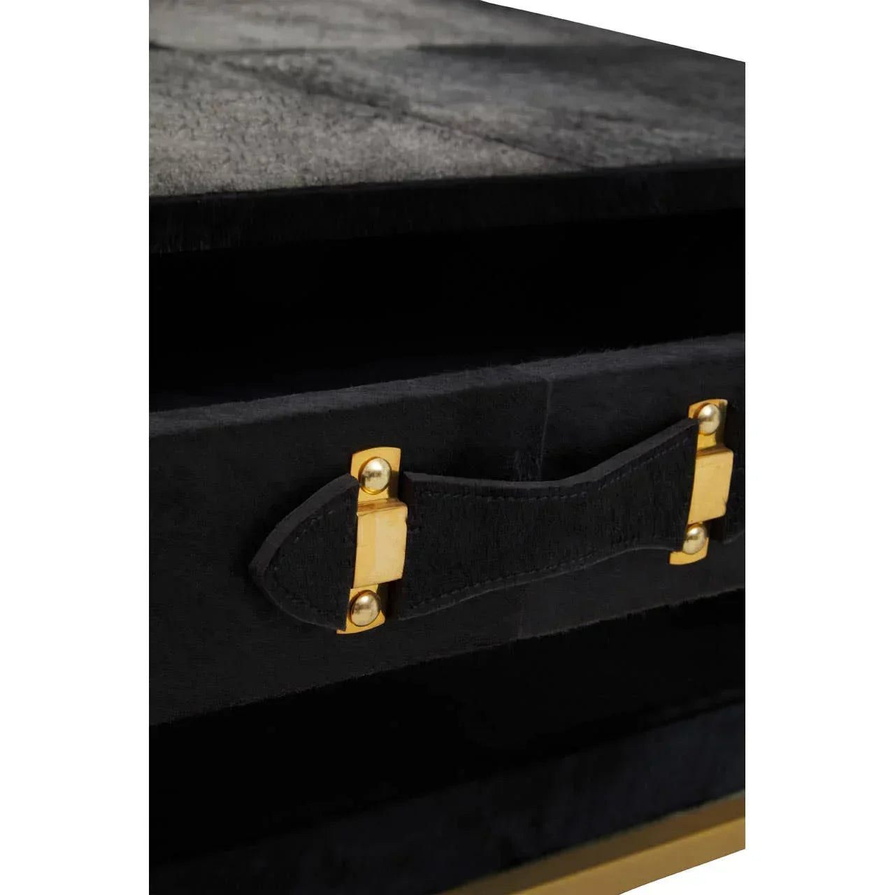 Close-up of black drawer handle with gold metal accents on velvet furniture