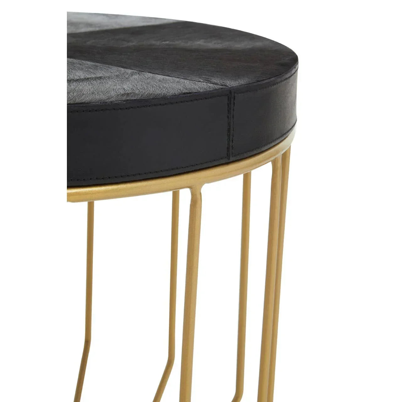Closeup of round side table with black upholstered top and gold metal legs