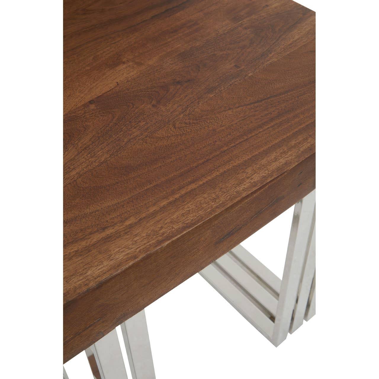 Closeup of wooden dining table with chrome legs, showing smooth tabletop and modern frame