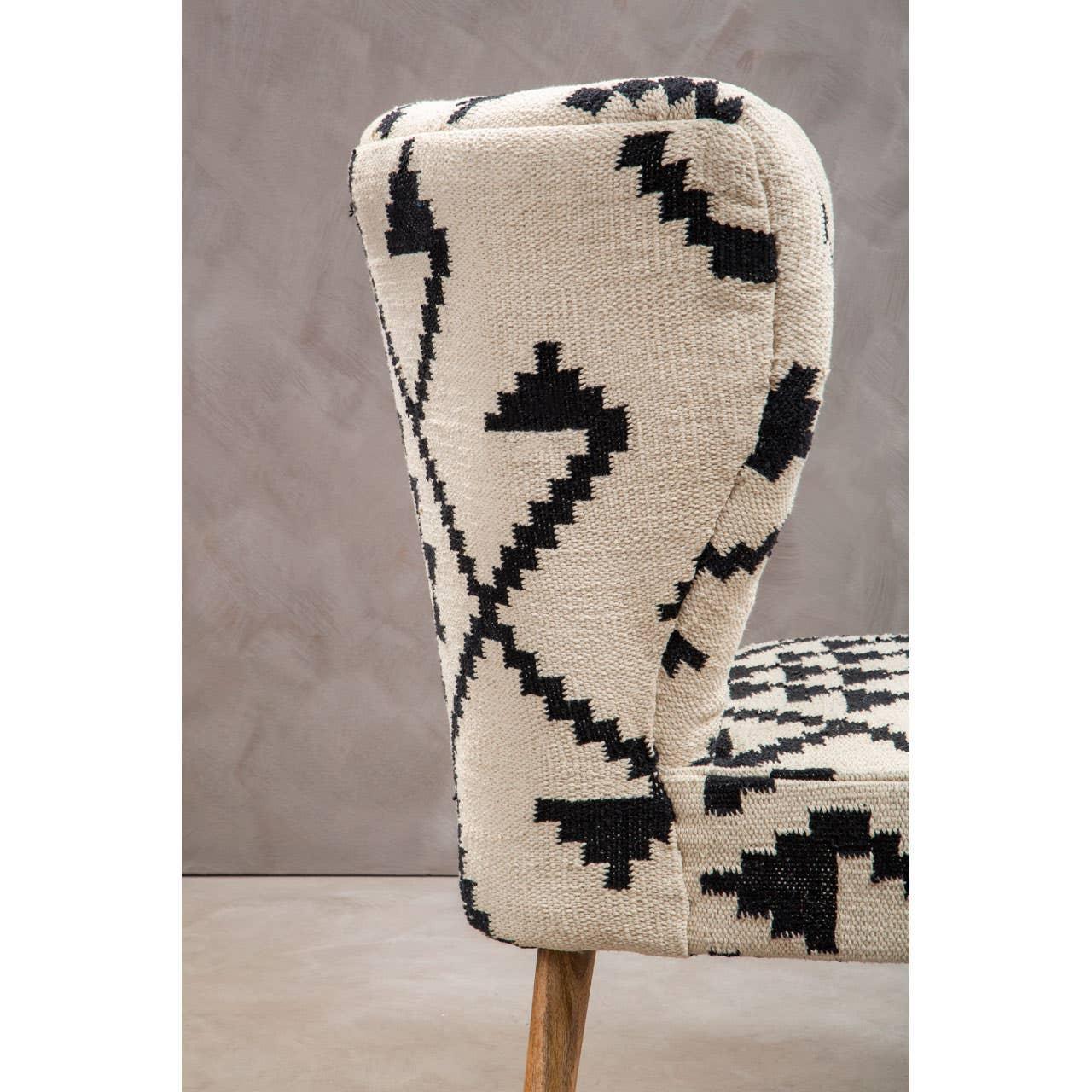 Accent chair with cream and black geometric upholstery and wooden legs, side angle view