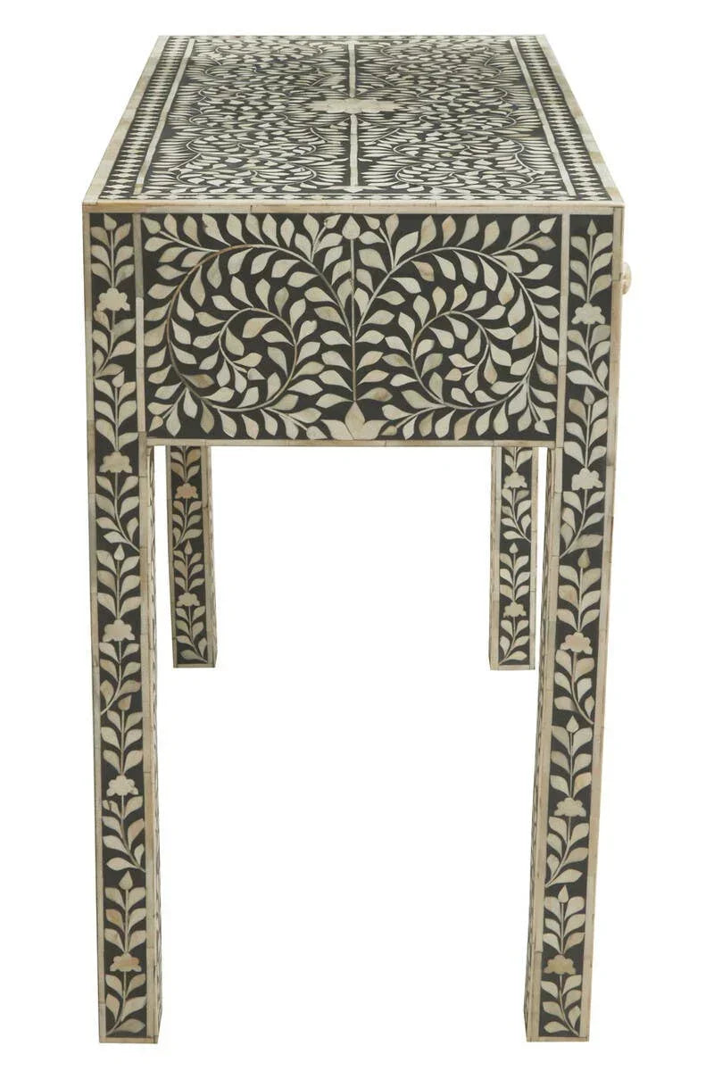 Black console table with white floral bone inlay pattern, viewed from front angle