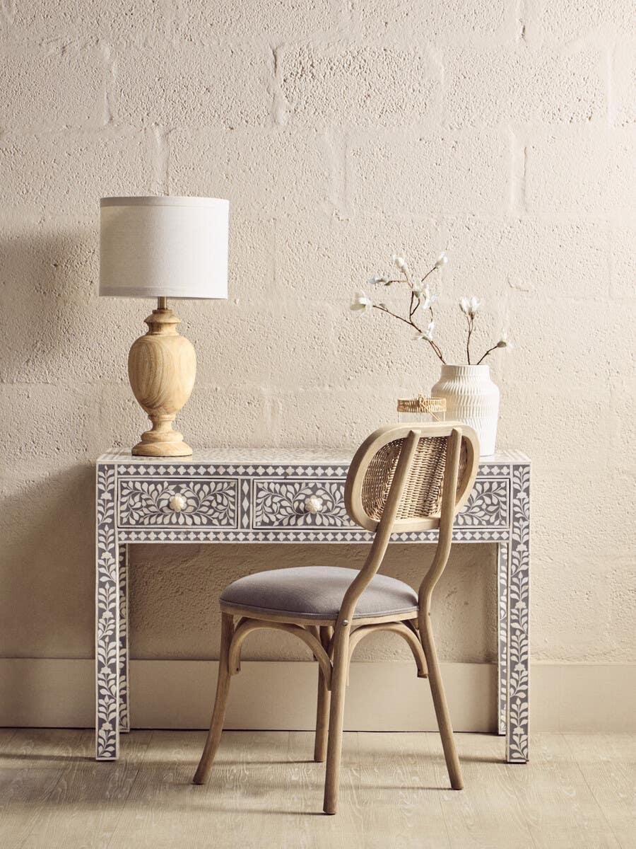 Bone inlay console table with patterned drawers, lamp, chair, and ceramic vase