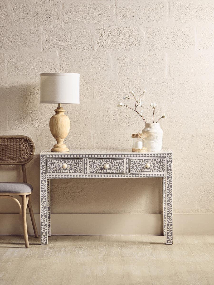 Bone inlay console table with floral pattern, three drawers, styled with lamp and vase