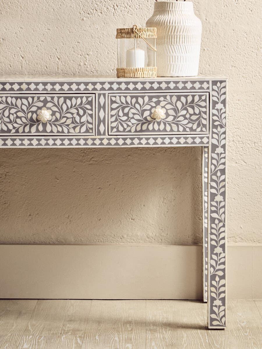 Grey bone inlay console table with floral pattern, two drawers, candle holder and vase on top