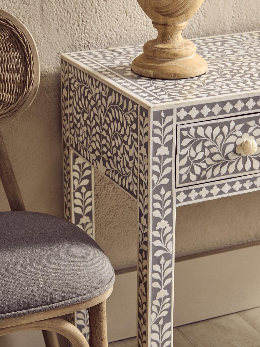 Bone inlay console table with floral pattern beside cushioned wooden chair