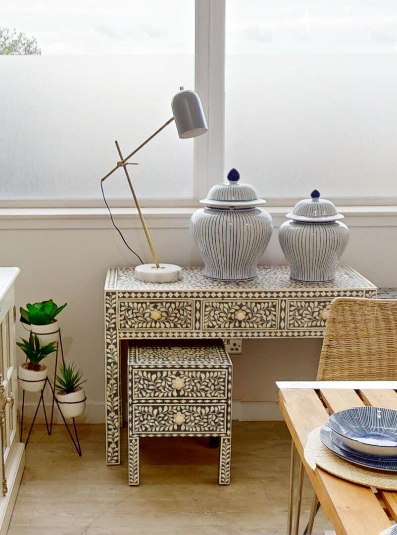 Floral inlay console table with ceramic jars, table lamp, and nested side table