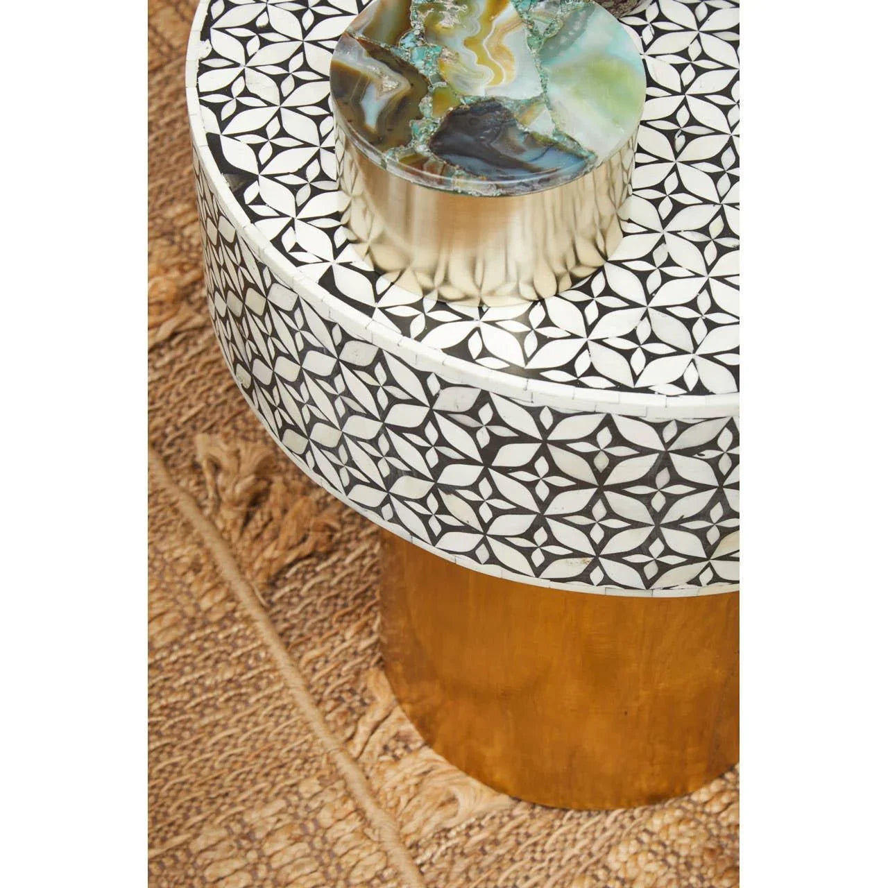 Round side table with geometric inlay pattern and brass base on woven rug