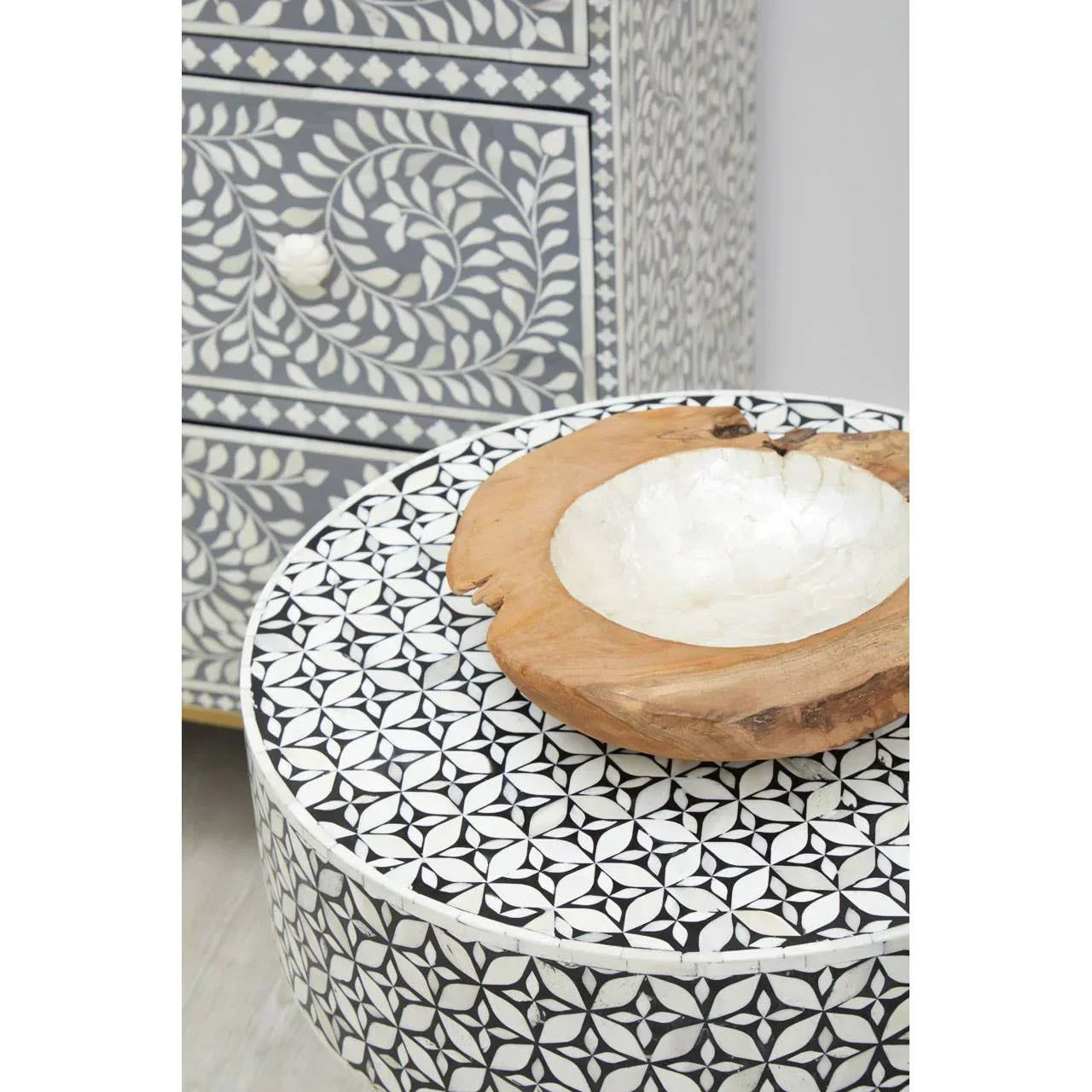 Black and white inlay side table with geometric pattern and wooden decorative bowl on top