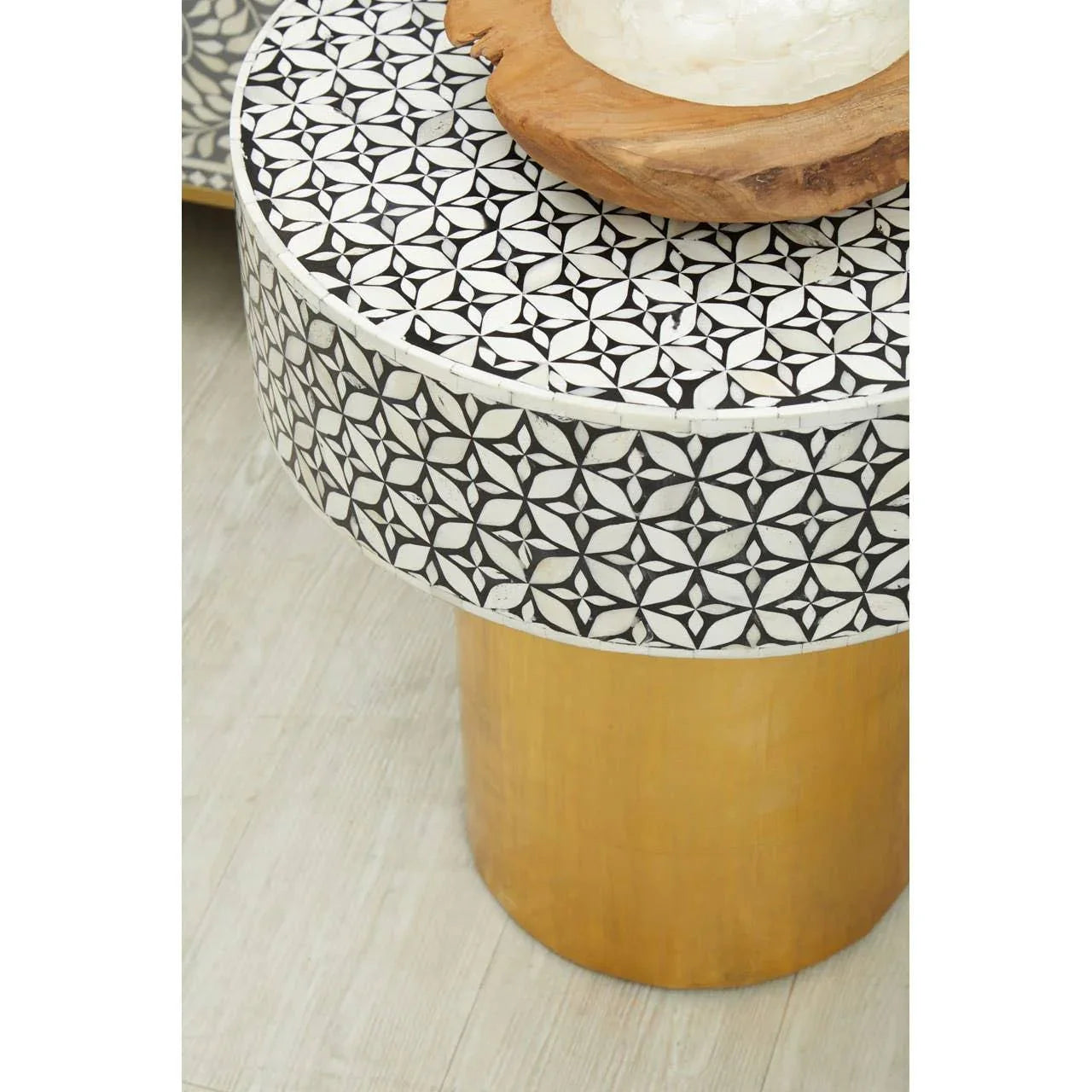 Round side table with black and white mosaic top and gold cylindrical base on wood floor
