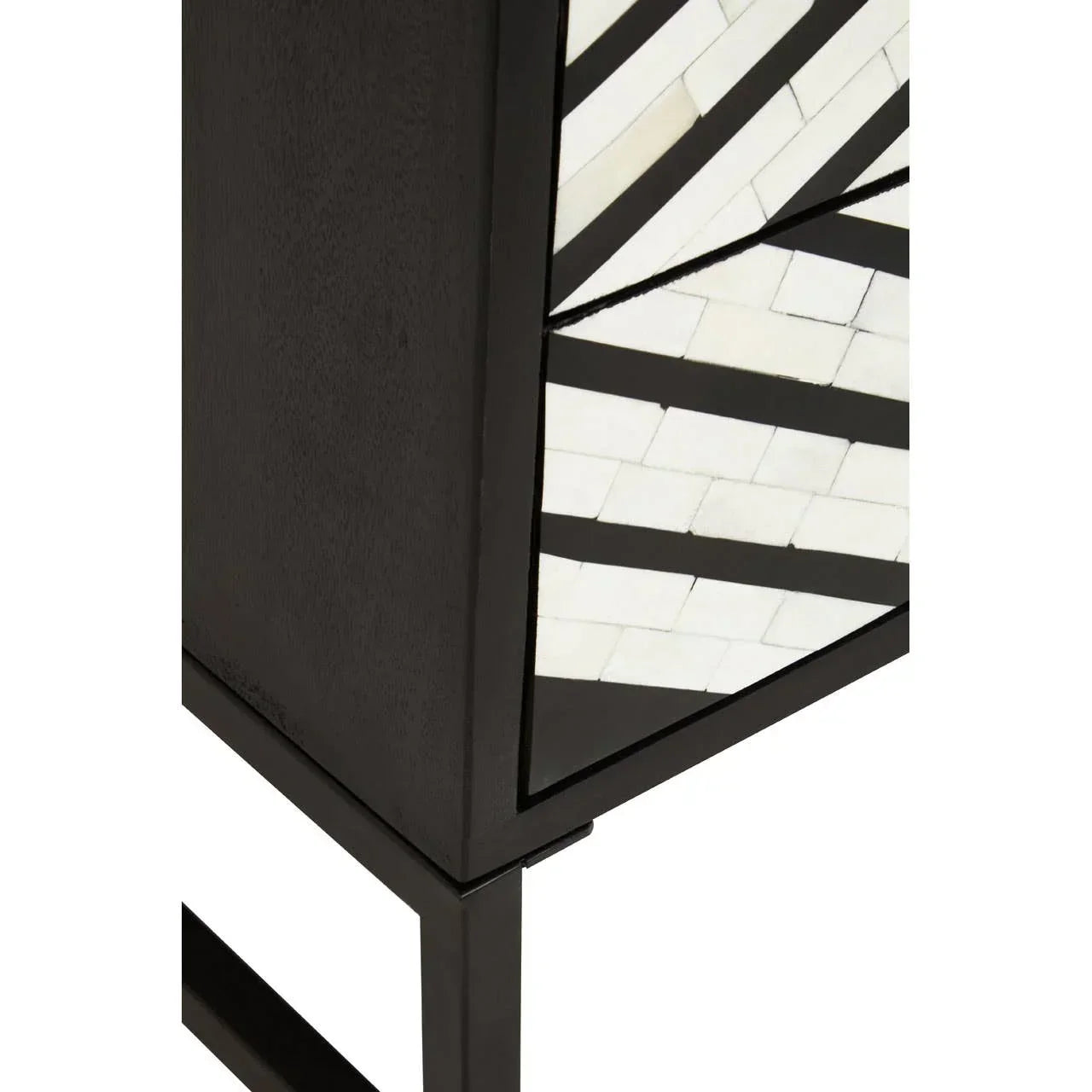 Black wooden cabinet corner with geometric white and black inlay detail on metal legs