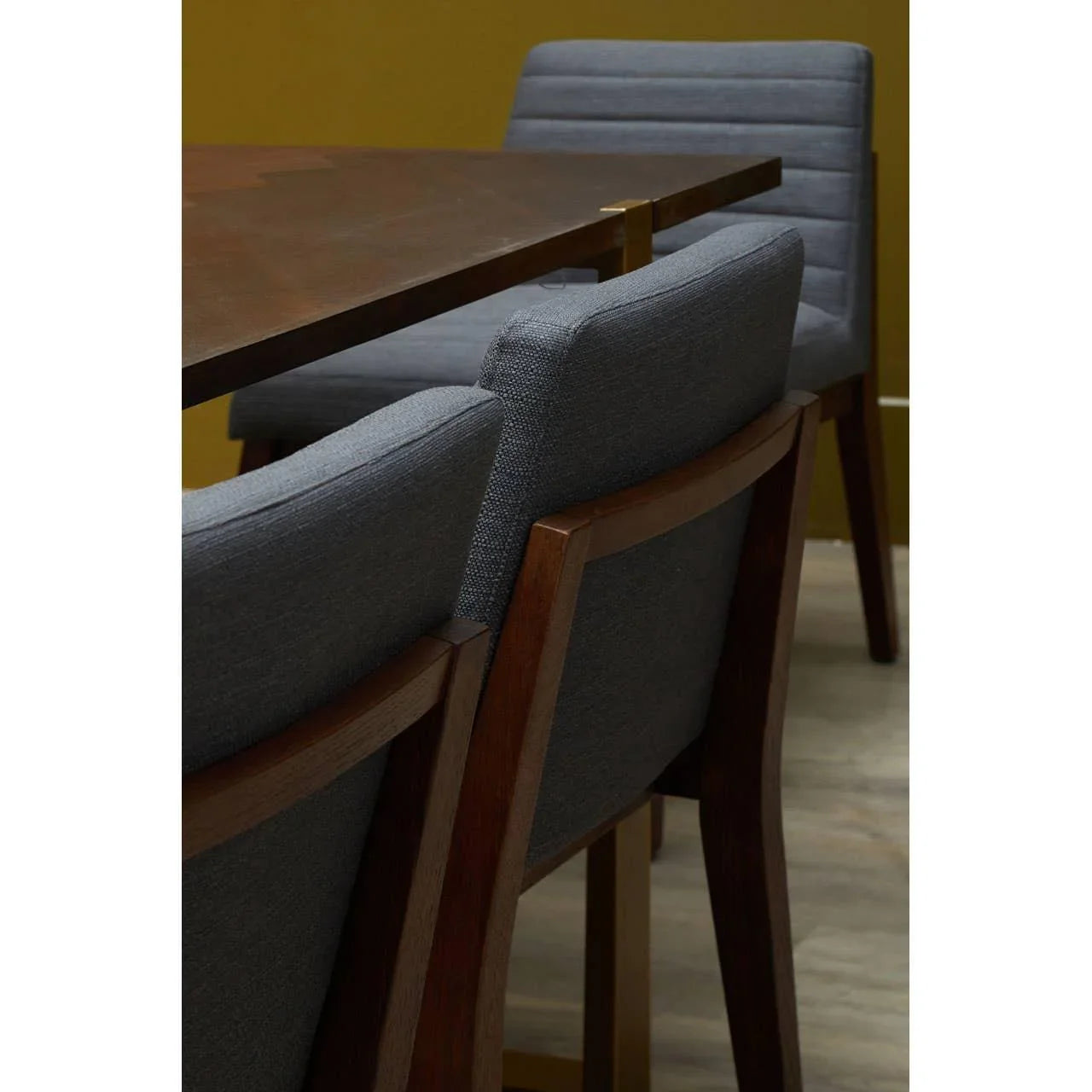 Dark wood dining table with grey upholstered dining chairs on a wooden floor