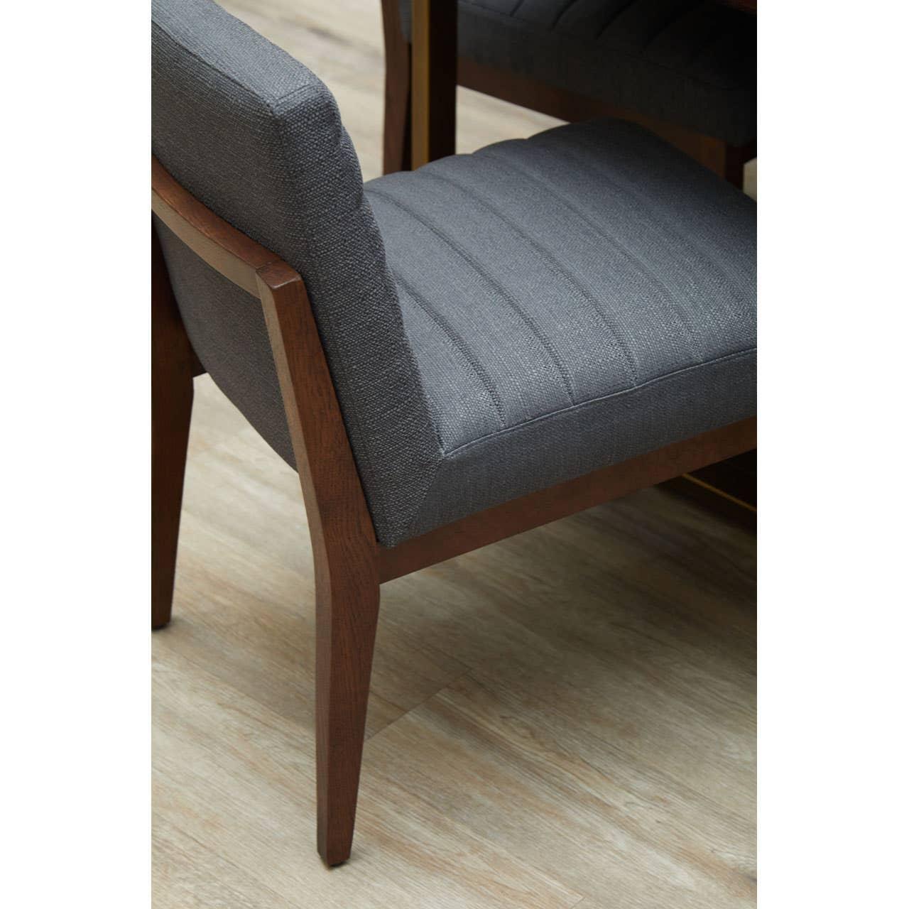 Dark grey upholstered dining chair with wooden frame on light wood flooring