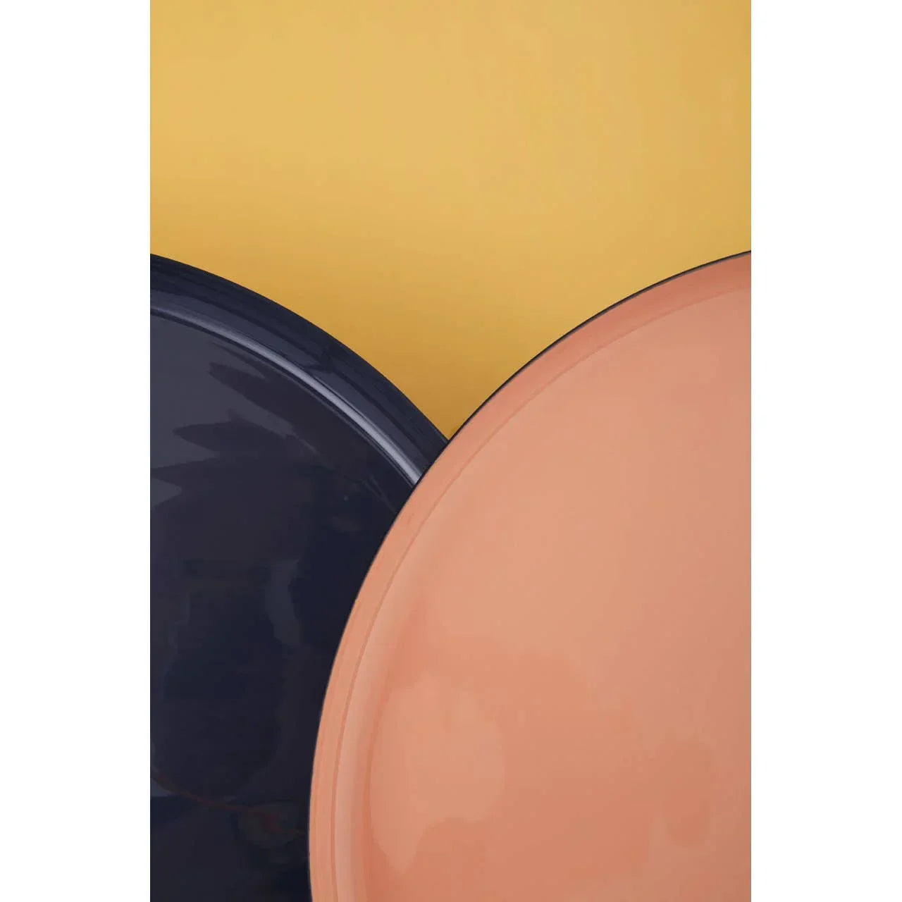 Closeup of peach and navy ceramic plates overlapping on a yellow background