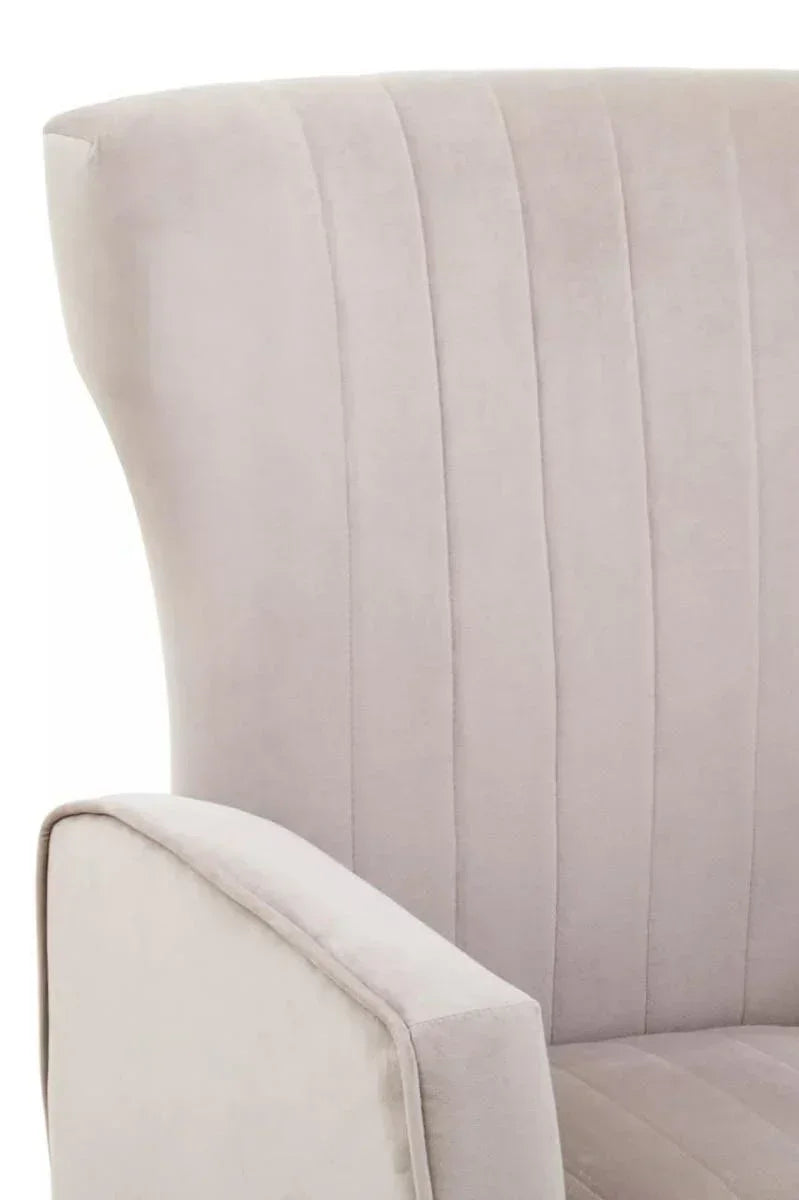 Beige velvet armchair with vertical stitched backrest, partial side view