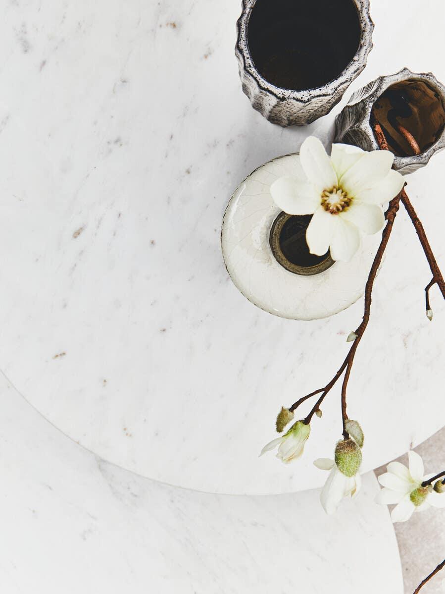 White marble coffee table with ceramic vases and fresh flowers top view