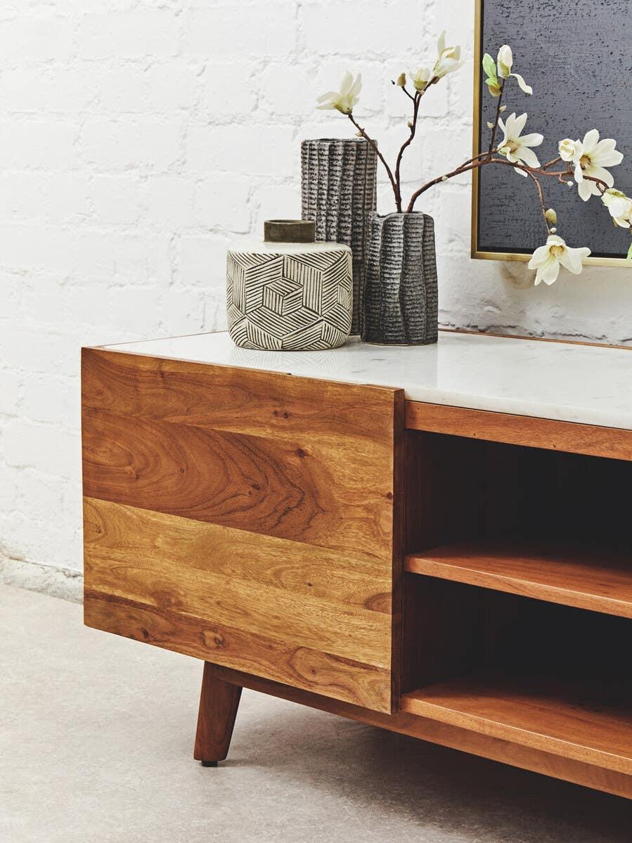Wood TV unit with open shelving, white top, and decorative vases with flowers