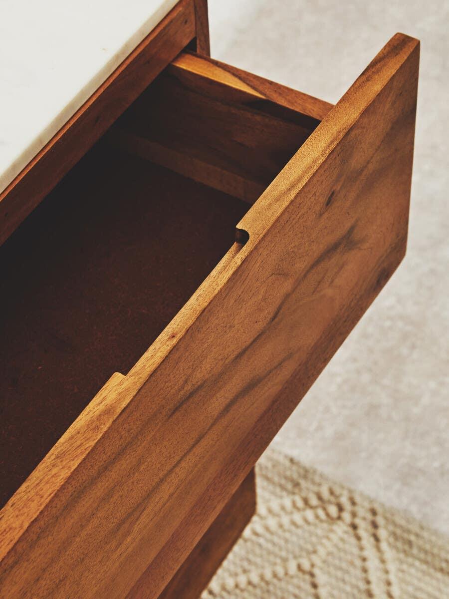 Close-up of wooden drawer with marble top and handle detail on textured carpet