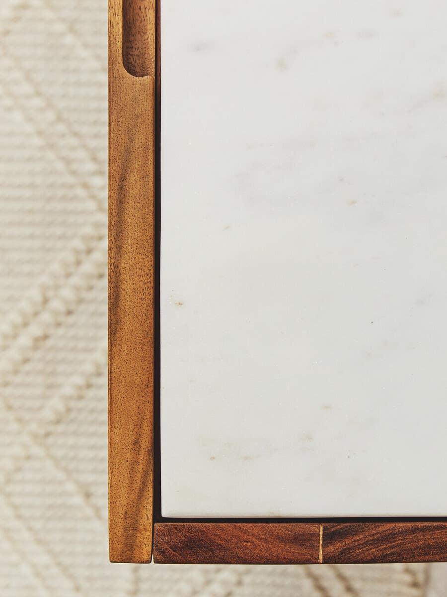 Corner of wooden coffee table with white marble top on textured rug