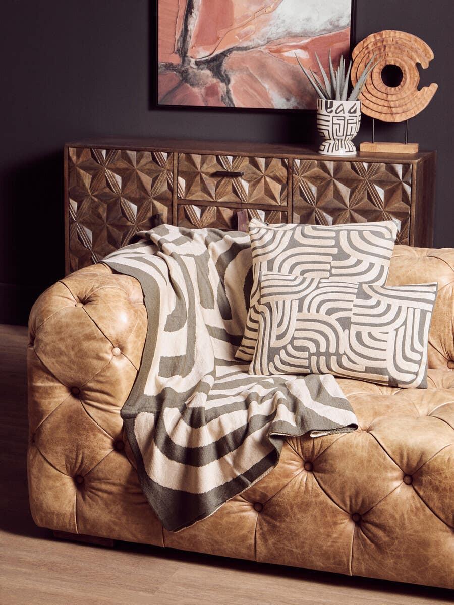 Tan leather sofa with tufted design, geometric cushion and matching throw blanket
