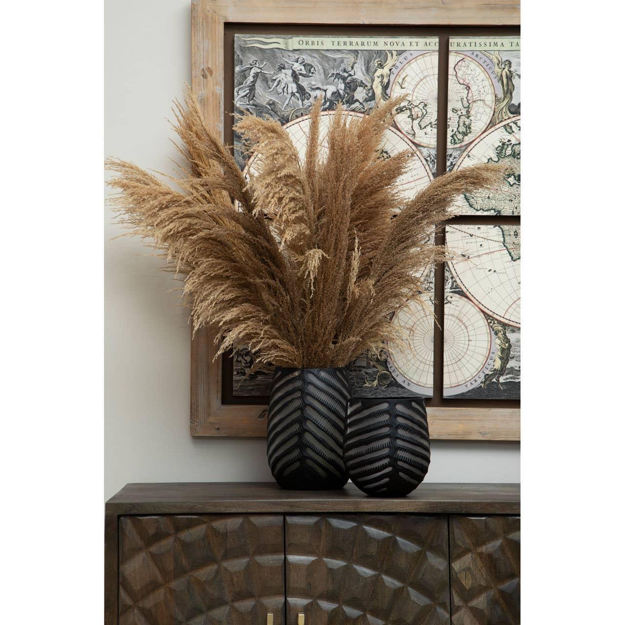 Brown pampas grass in black textured vases on carved wood sideboard with vintage map art