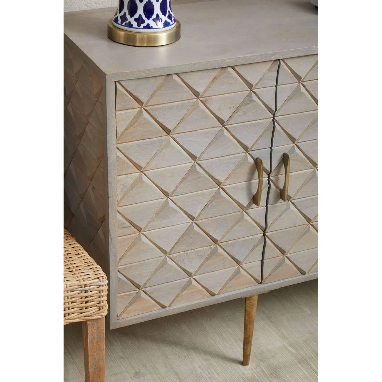 Wooden sideboard with geometric carved doors, brass handles, and tapered legs
