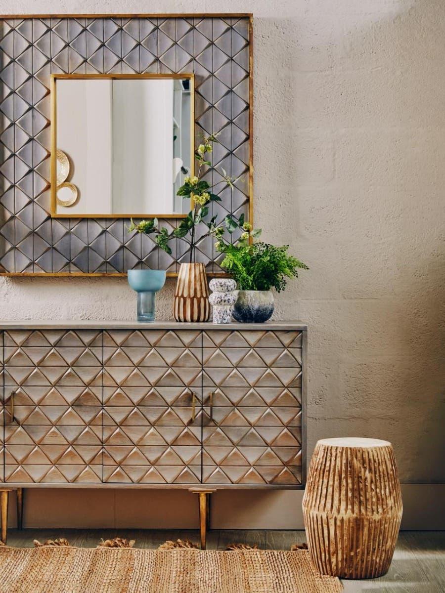 Geometric wood sideboard with gold handles, wall mirror, and decorative vases in modern interior