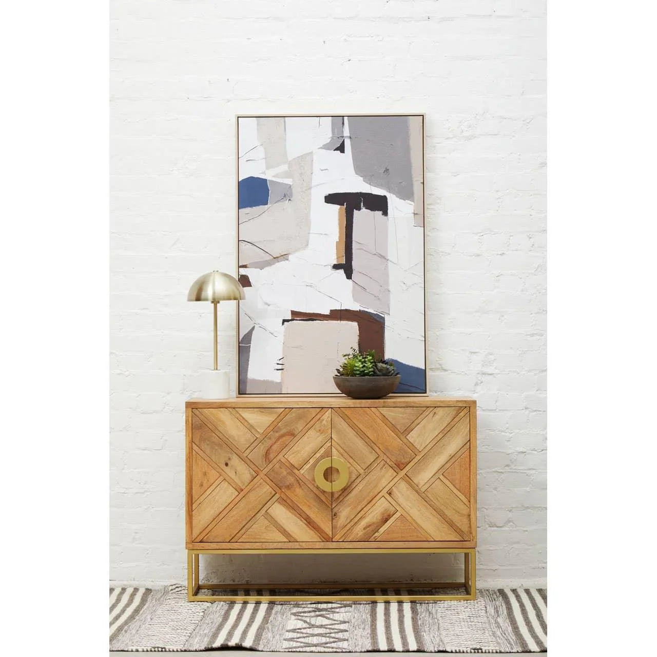 Wooden sideboard with geometric pattern, gold base, abstract art, lamp and plant decor