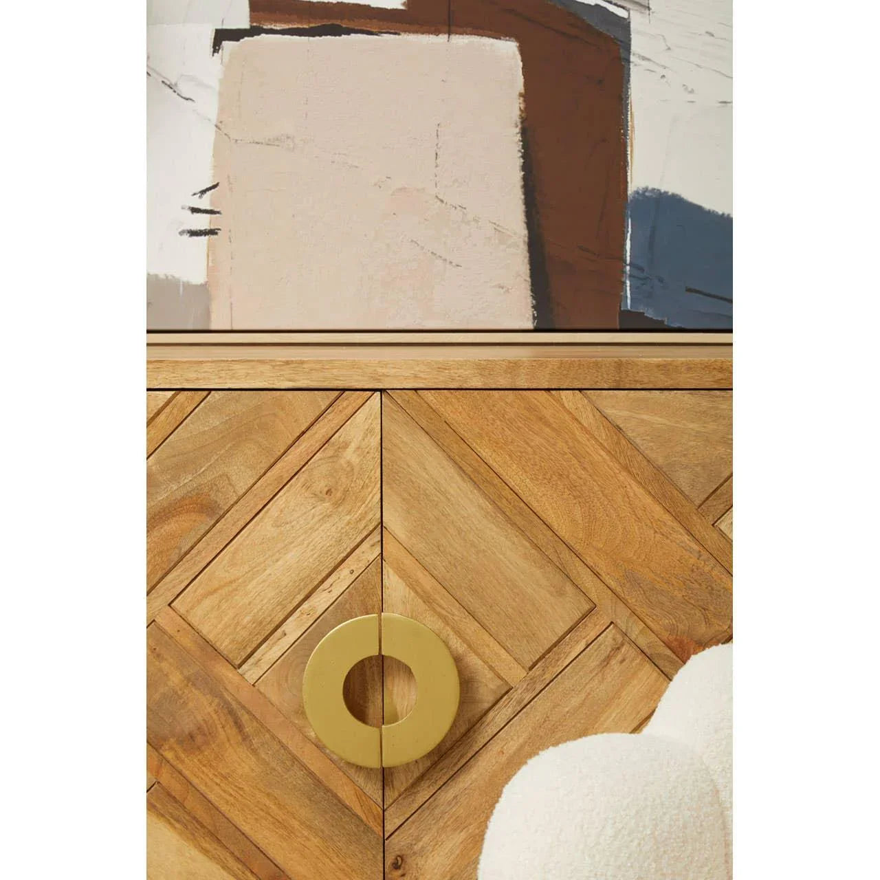 Chevron pattern wooden sideboard with large gold circular handle and abstract art above
