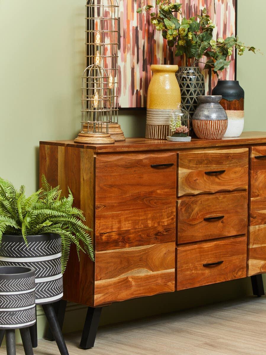 Solid wood sideboard with drawers, decorative vases, lamp, and indoor plants