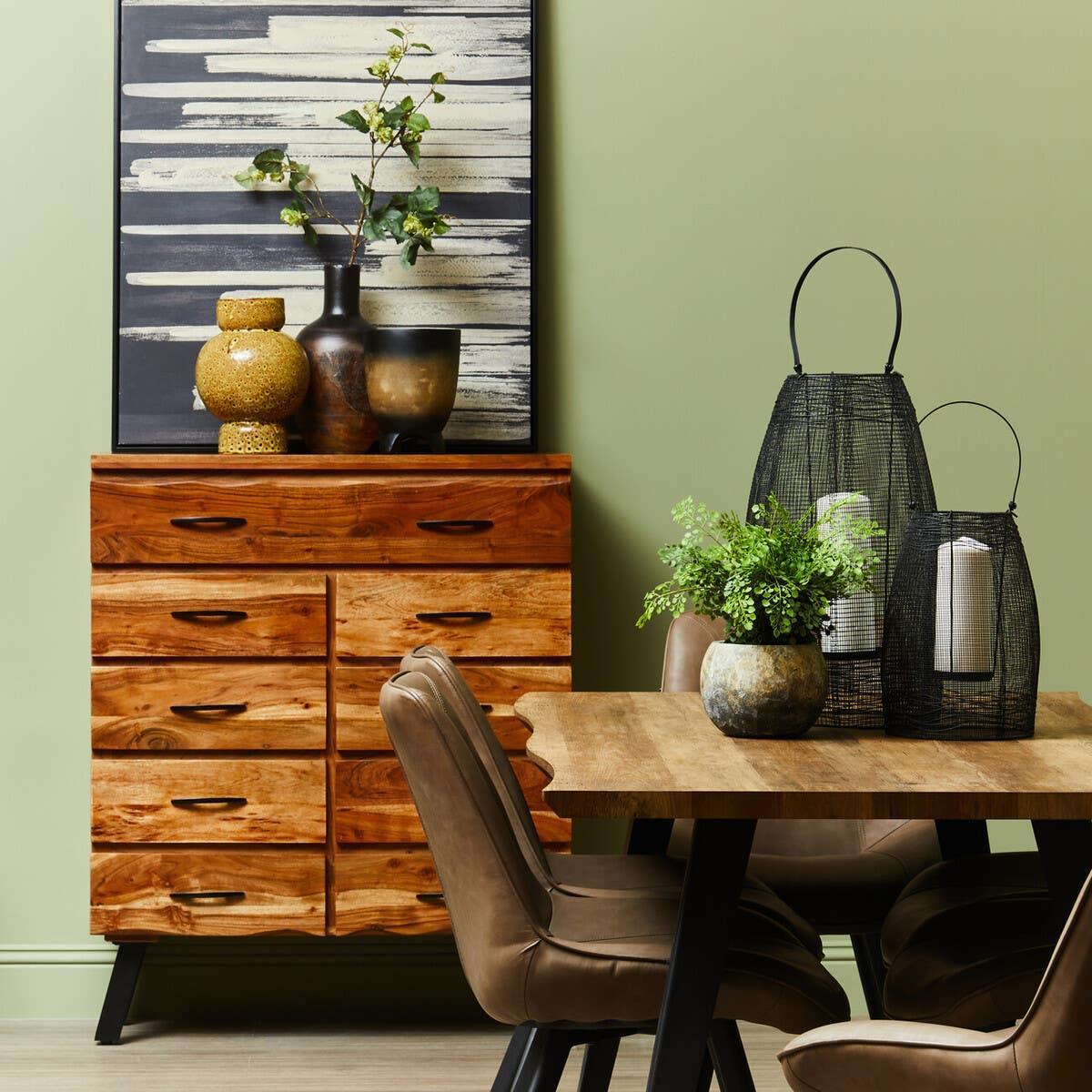 Solid wood chest of drawers with natural finish beside oak dining table and brown chairs